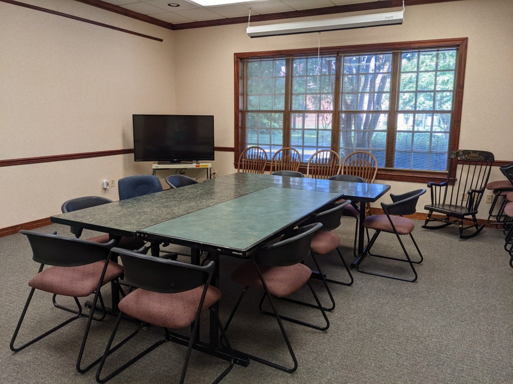 Photo of meeting room with two tables and chairs around them,