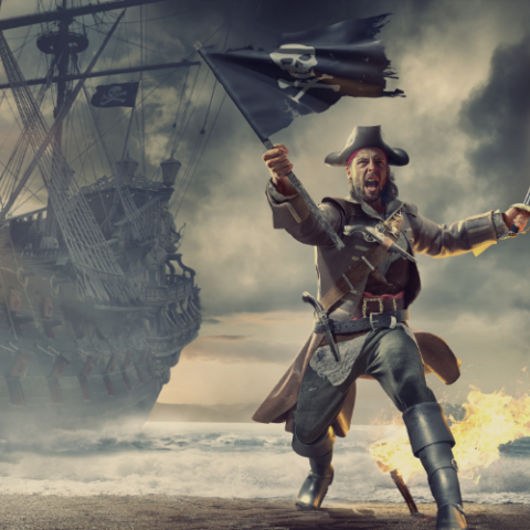 Grimacing pirate coming ashore on the beach while waving his jolly roger.  Flames and pirate ship in the background.