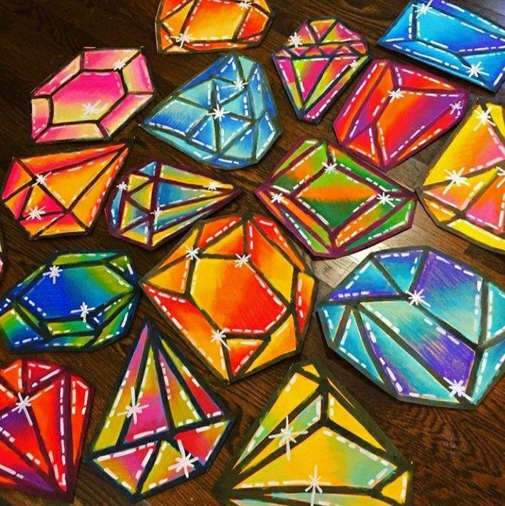 Colorfully painted 2 dimensional gemstones in all shapes and sizes laid out on a black background